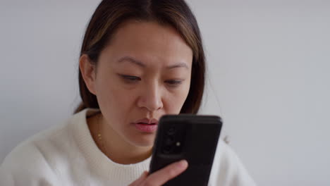 Close-Up-Of-Stressed-Anxious-Woman-At-Home-Reacting-To-Internet-Or-Social-Media-News-Message-Or-Story-On-Mobile-Phone